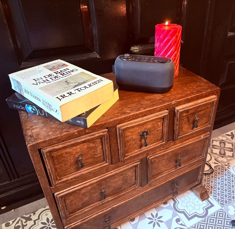 Eikenhouten ladekastje met twee boeken, een radiootje en een rode kaars erop