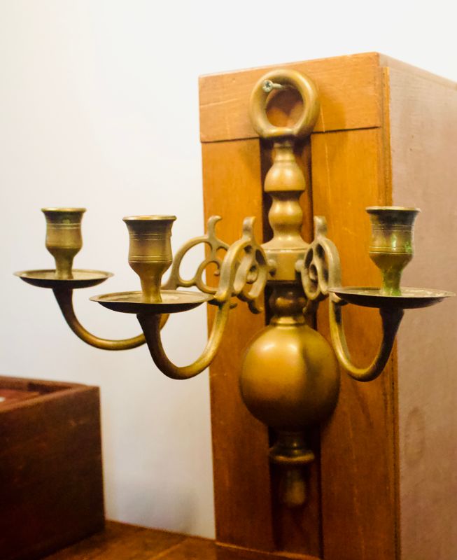 Vintage messing wandkandelaar met drie armen, bolvormige kern en sierlijke krulmotieven detail.