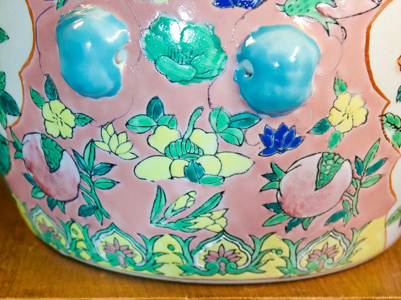 Zijaanzicht van porseleinen pot met reliëfdetails en blauwe handgrepen.