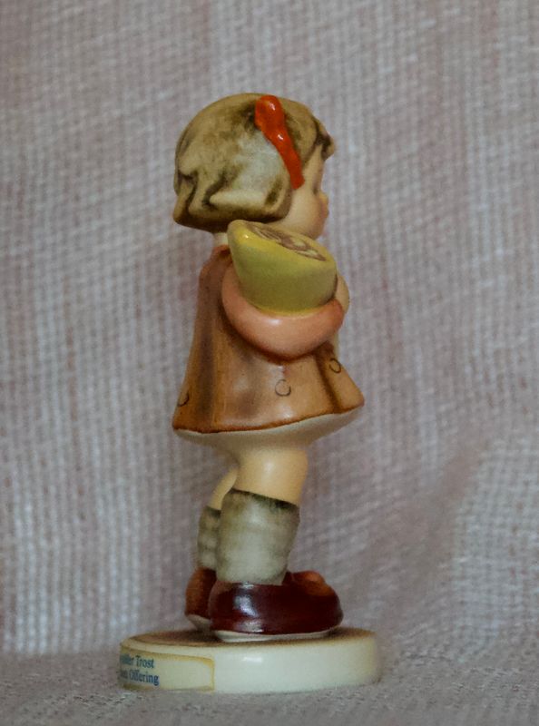Linker zijkant van vintage porseleinen Goebel Hummel meisje met bruin jurkje en blonde haren.
