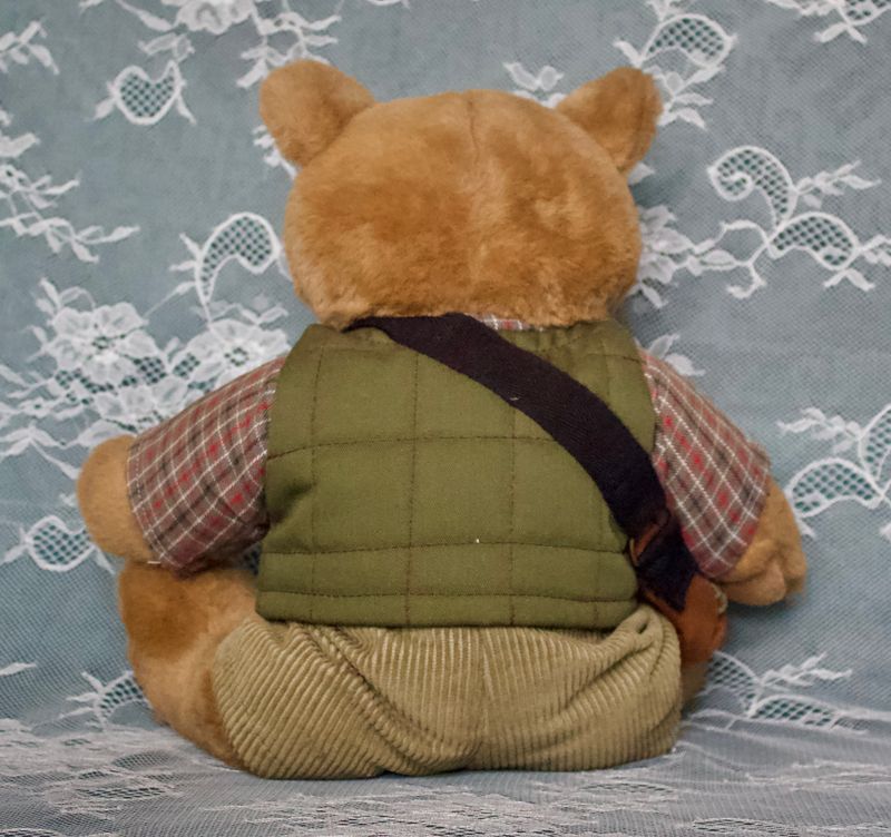 Achterkant teddybeer met groene vest en schoudertas, corduroy broek.