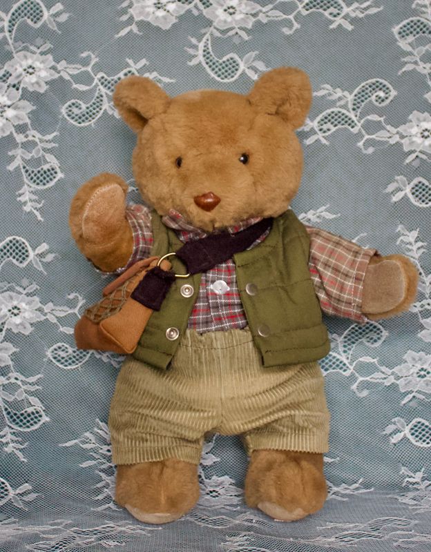 Teddybeer in jachtkleding met ruitjesoverhemd, groen bodywarmer en schoudertas