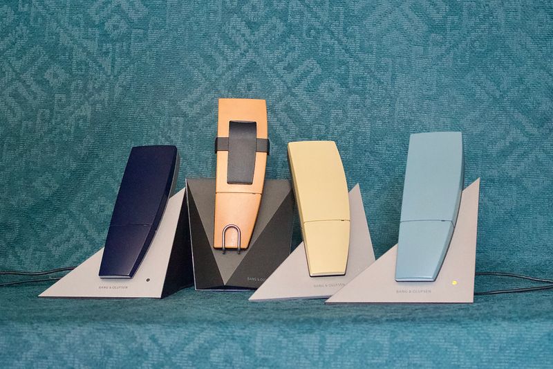 Vier draadloze telefoons in donkerblauw, zalm, geel en lichtblauw op hun laders