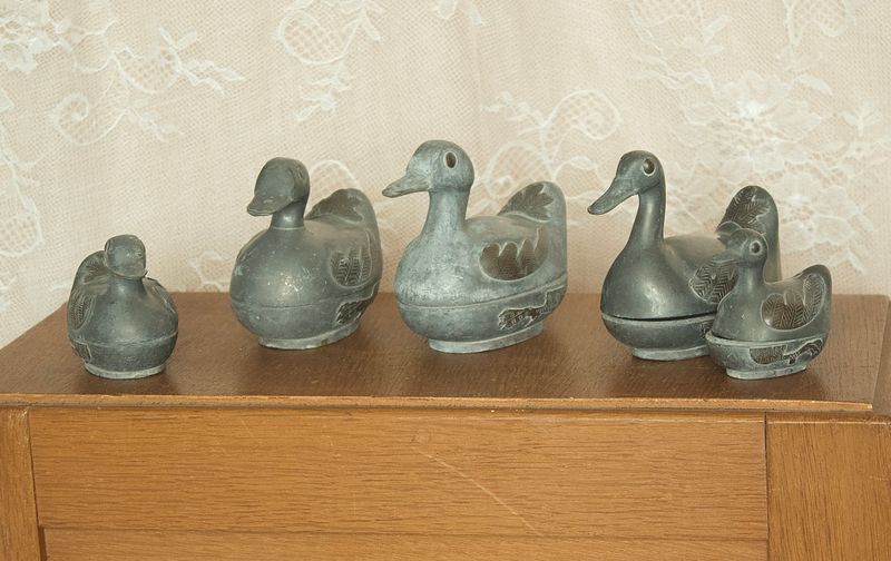 Set of 5 vintage pewter duck trinket boxes on a wooden table, 3 large and 2 small ones.