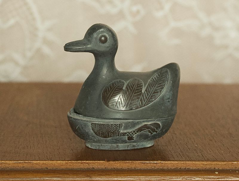 Zijaanzicht van klein tinnen eendje opbergdoosje met gedetailleerde vleugels in reliëf