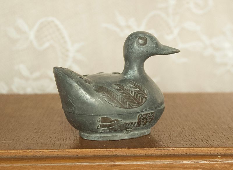Zijaanzicht van klein tinnen eendje opbergdoosje met gedetailleerde vleugels in reliëf