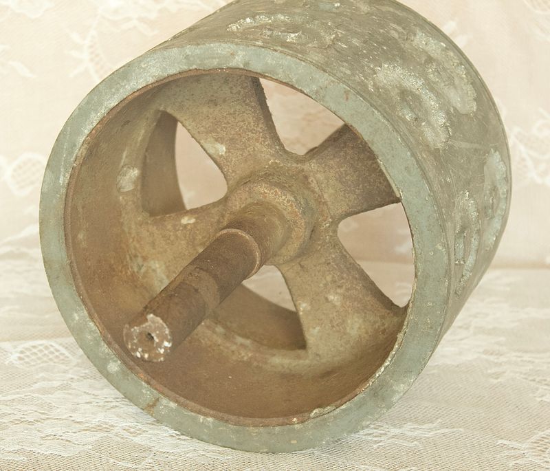 Antieke metalen deegroller, die de binnenstructuur, de centrale as en de spaken laat zien.