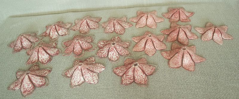Patroonweergave van meerdere clusters van roze glazen Murano-bloemen die de onderkant van de kroonluchter versieren.