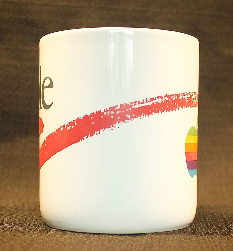 Zijaanzicht van de vintage Apple-mok met rode penseelstreek en het zijaanzicht van het regenbooglogo