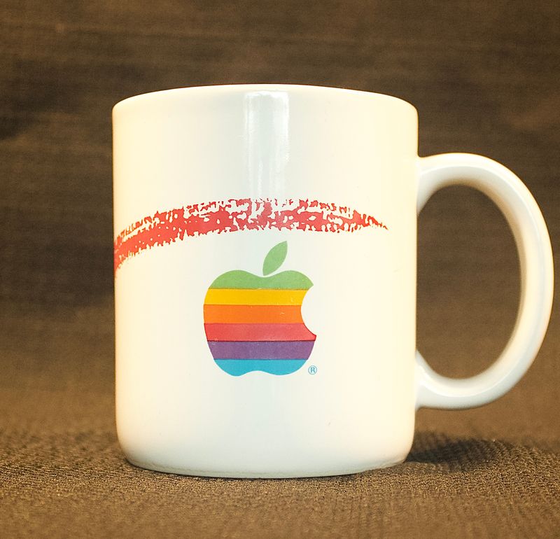 Achterkant van de vintage Apple-mok met het iconische zeskleurige regenbooglogo en oortje.