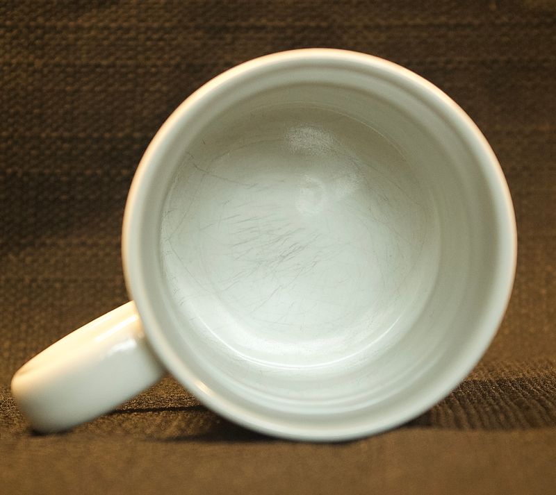 Bovenaanzicht van de binnenkant van de witte vintage Apple-mok met lichte sporen van gebruik op de bodem.
