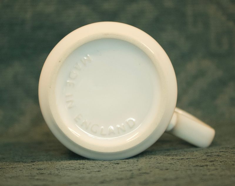 Onderaanzicht van de vintage Apple-mok, waarop de gestanste tekst "MADE IN ENGLAND" duidelijk zichtbaar is op de witte bodem.