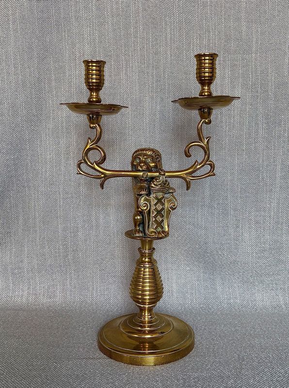 Tweearmige messing kandelaar met een leeuwenfiguur tussen de armen
