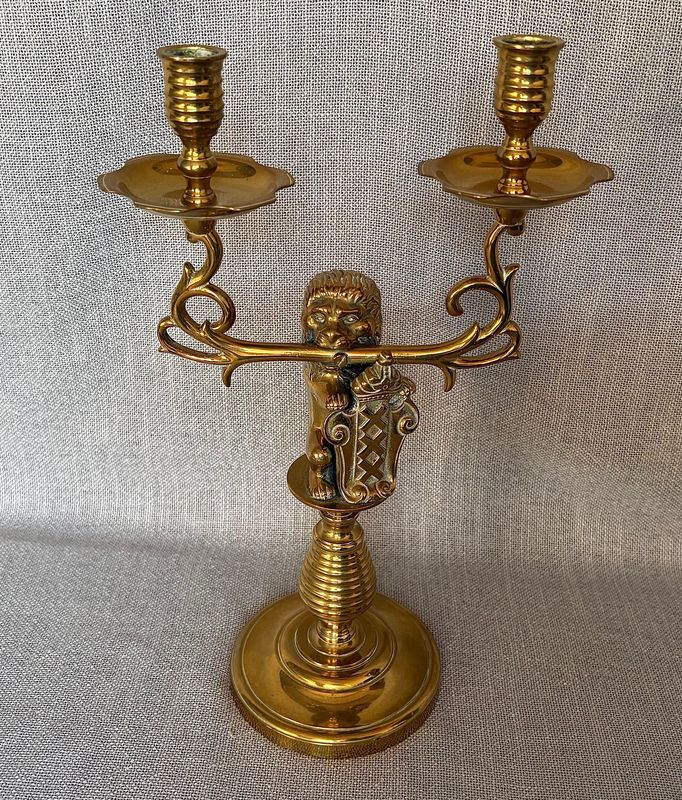 Zijaanzicht van de zware messing kandelaar met de leeuwenfiguur, gedetailleerde armen en geribbelde voet.