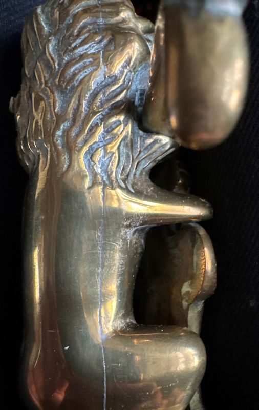 Close-up van de originele patina en gietstructuur op het messing oppervlak van het leeuwenfiguur.