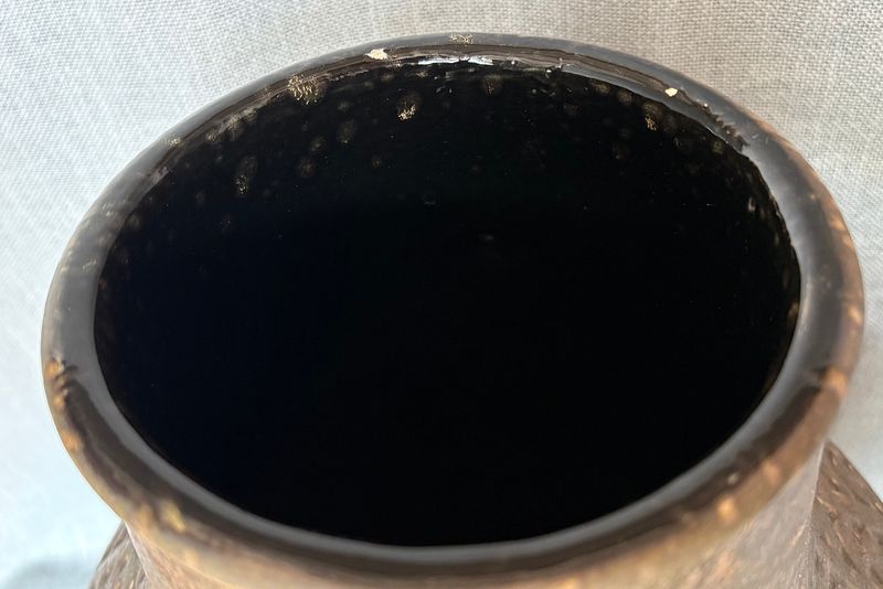 Close-up van de bovenrand en de donkere glazuurlaag aan de binnenzijde.