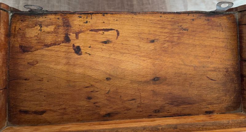 Achterzijde van het houten kastje met houten achterwand en twee metalen ophangogen.