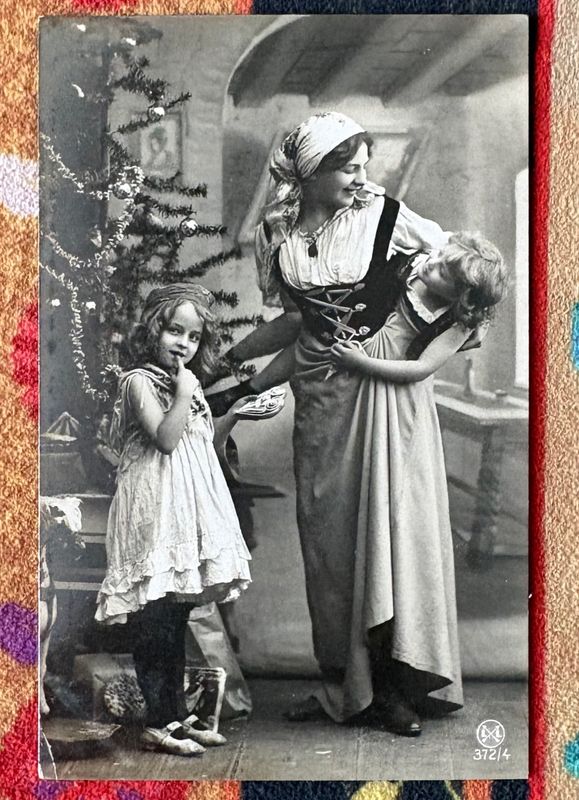 Antieke kerstfotokaart, vrouw in kostuum met twee meisjes bij een versierde kerstboom
